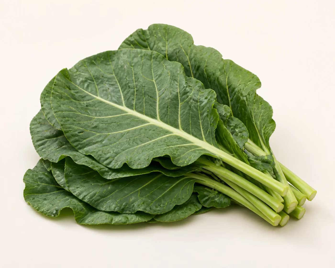 Fresh Collard Greens arranged on a warm off-white surface.