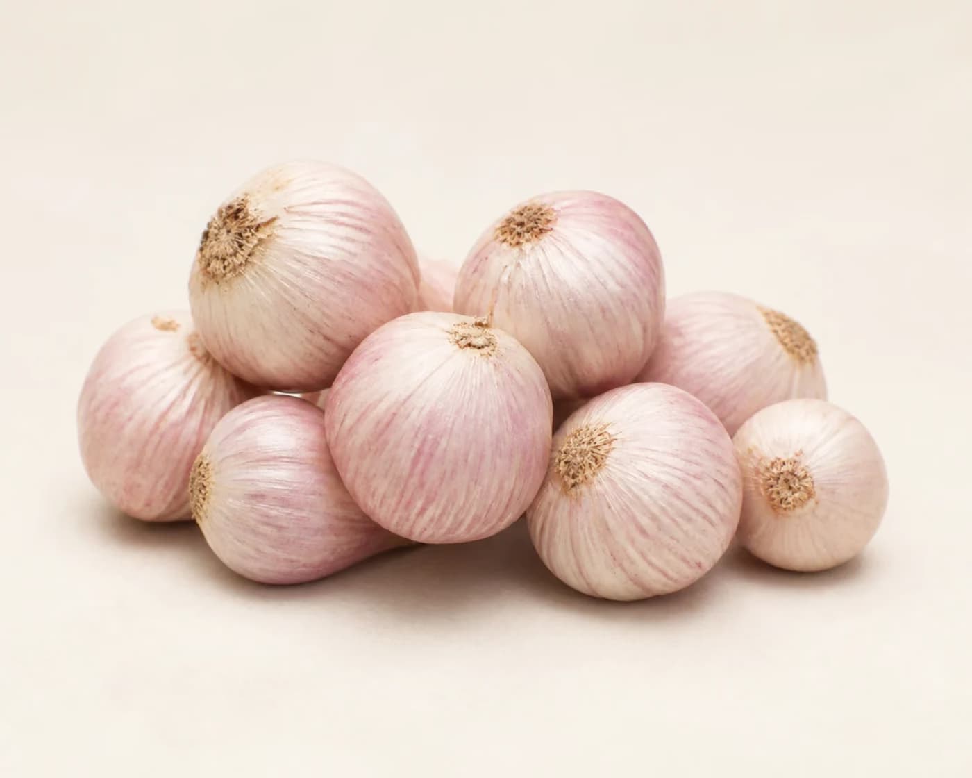 Fresh Single Clove Himalayan Garlic arranged on a warm off-white surface.