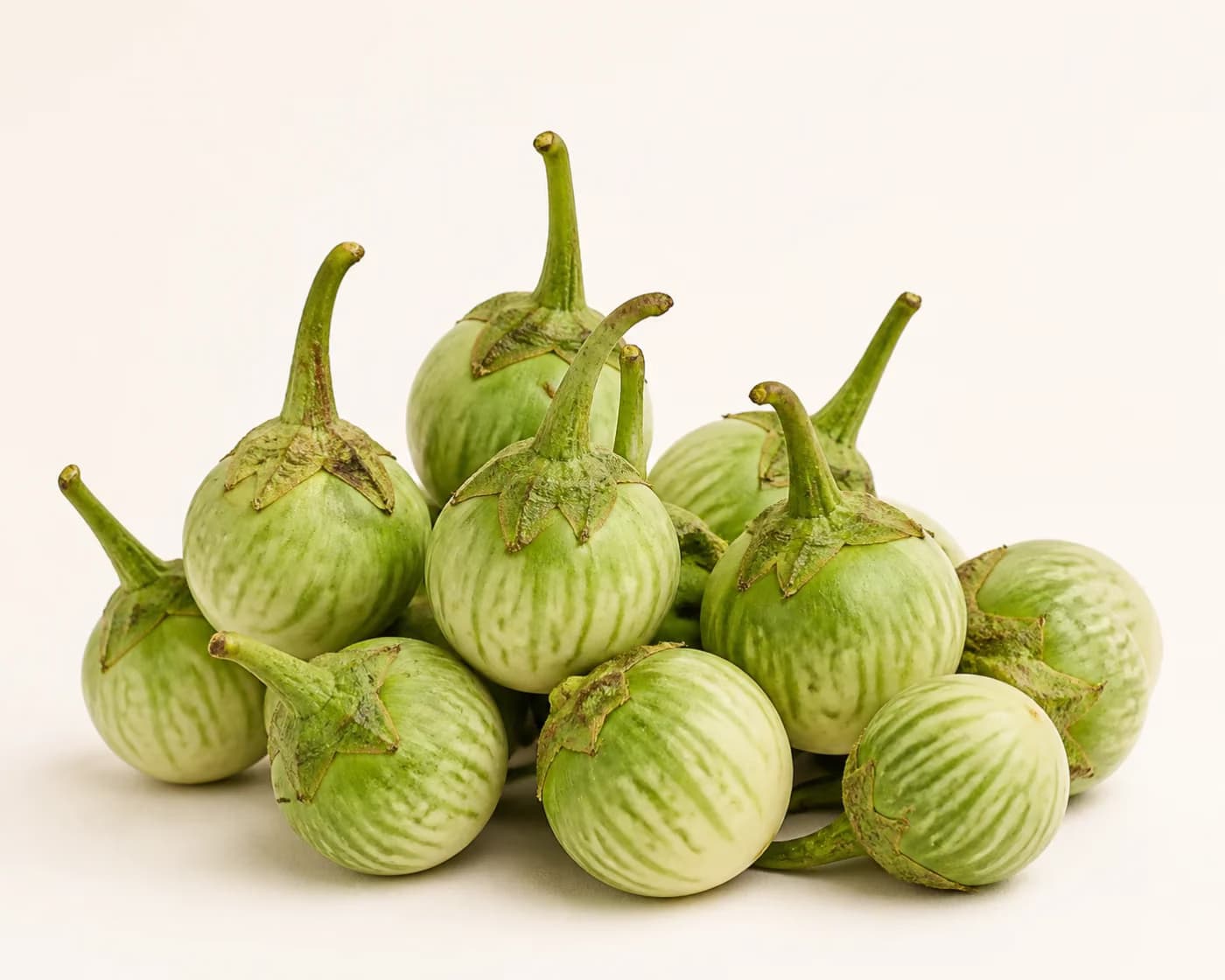 Fresh Thai Green Brinjal arranged on a warm off-white surface.