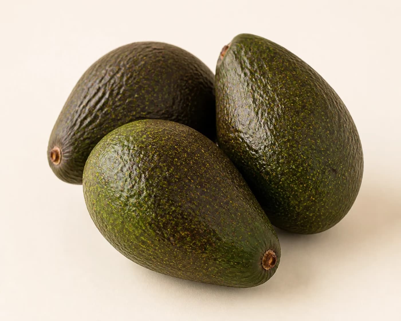 Fresh Fuerte Avocado arranged on a warm off-white surface.